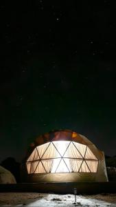 una gran cúpula con una luz en ella por la noche en Bronze Mountains Camp Wadi Rum en Áqaba