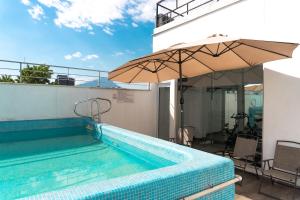 a swimming pool with an umbrella next to a building at Hotel Boutique de Firma in Monterrey