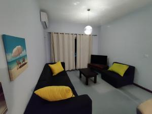 a living room with a black couch and yellow pillows at Ashiana OceanSide Apartment in Flic-en-Flac