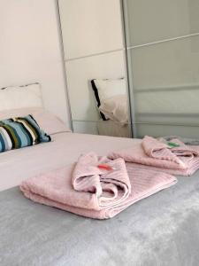 een bed met roze handdoeken voor een spiegel bij Apartamento La Doncella in Alcalá de Henares