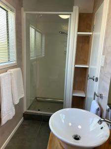 a bathroom with a glass shower and a white sink at Evolve Bach in Whitianga