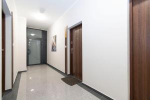 a hallway with white walls and a wooden door at Apartament UKIEL PARK 7 przy Plaży Miejskiej - klimatyzacja,free parking,FV in Olsztyn