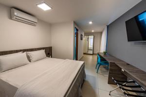 a bedroom with a bed and a desk and a television at Hotel Mais1 in Campina Grande