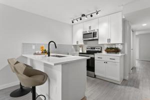 una cocina blanca con armarios blancos y fregadero en UNIVERSITY SERENITY SUITES, en Tampa