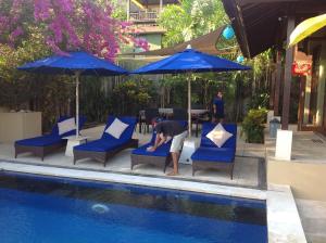 a man sitting in blue chairs next to a pool at Villa Penyon in Nusa Lembongan
