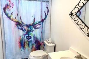 a bathroom with a painting of a deer shower curtain at Four Season Cottage with Wood Burning Sauna in Ompah