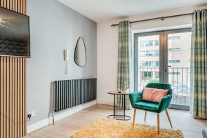 a living room with a green chair and a table at Citygate Central Apartments in Belfast