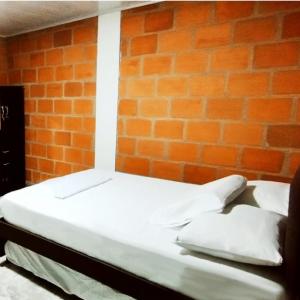 łóżko w pokoju z ceglaną ścianą w obiekcie GREEN APARTMEN "El Jardín" w mieście Girón
