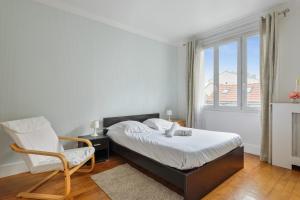 ein Schlafzimmer mit einem Bett und einem Stuhl und einem Fenster in der Unterkunft Appartement Voltaire - Welkeys in La Garenne-Colombes