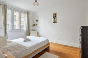 ein weißes Schlafzimmer mit einem Bett und einem Fenster in der Unterkunft Appartement Voltaire - Welkeys in La Garenne-Colombes