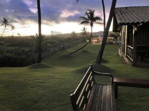 un banc en bois assis dans l'herbe à côté d'une maison dans l'établissement Apartamento Doce Lar Resort Treebies Subauma, à Subaúma
