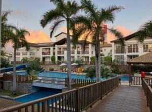 苏巴乌马Apartamento Doce Lar Resort Treebies Subauma的有游泳池和棕榈树的度假村