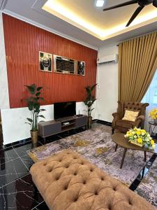 a living room with a couch and a tv at Rania Riverview Guesthouse #BestGuesthouseInTown #SpaciousLivingRoom #ModernClassicConcept #LuxuryDiningset #freeWifi #Netflix #FullyAircond #CozyPrayerSpace in Kuala Berang