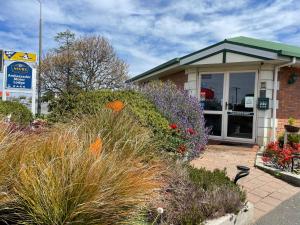 un edificio con fiori e piante di fronte di ASURE Ambassador Motor Lodge a Oamaru