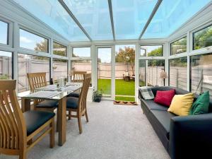 a conservatory with a couch and a table and chairs at Downsview Cottage in Lyminster