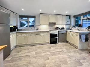 a large kitchen with white cabinets and wooden floors at Downsview Cottage in Lyminster