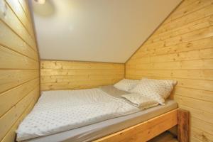 a small room with a bed in a wooden cabin at Osada Sroczy Jar in Rozpucie