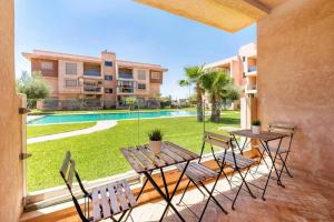 une terrasse avec une table, des chaises et une piscine dans l'établissement L’Unique appartement Z. Coralia, à Marrakech