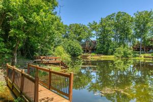 eine Holzbrücke über einen See mit einem Haus im Hintergrund in der Unterkunft Lakeview Hideaway by Sarah Bernard Chalets, with Firepit and Private Dock on a Quiet Lake in Innsbrook