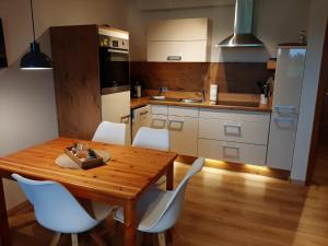 a kitchen with a wooden table and white chairs at Fewo Am Deich 1 Appartment 30 in Sankt Peter-Ording +3 photos