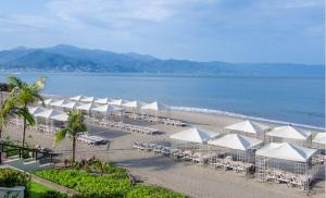 a beach with white umbrellas and chairs and the water at Oceanview Condo Vela Vallarta condo in Puerto Vallarta