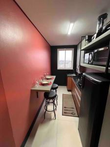 une petite cuisine avec une petite table et un mur rouge dans l'établissement Lindo e aconchegante, à Bento Gonçalves