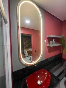 La salle de bains est pourvue d'un lavabo rouge et d'un miroir. dans l'établissement Lindo e aconchegante, à Bento Gonçalves