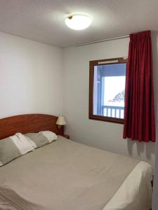 a bedroom with a white bed and a window at La Mongie T3 Duplex 8 personnes vue sur les pistes in Bagnères-de-Bigorre