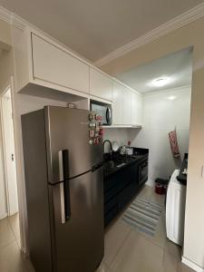 La cuisine est équipée d'un réfrigérateur en acier inoxydable et de placards blancs. dans l'établissement Hostel APÊ DO CRIS, à Florianópolis
