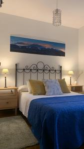 a bedroom with a large bed with a blue blanket at Al Viento, Alojamiento & Turismo Rural Prádena del Rincón in Prádena del Rincón