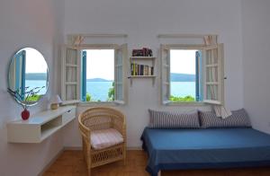 Schlafzimmer mit einem Bett, einem Stuhl und Fenstern in der Unterkunft Casa Kalypso in Steni Vala Alonissos