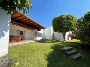 Alpuyeca的住宿－Casa Tabachin，后院,草坪上有一棵树和一座房子