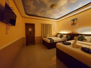 a hotel room with two beds and a flat screen tv at New Village Lodge in Oslob