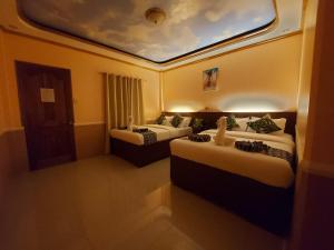 une chambre d'hôtel avec deux lits et un plafond dans l'établissement New Village Lodge, à Oslob