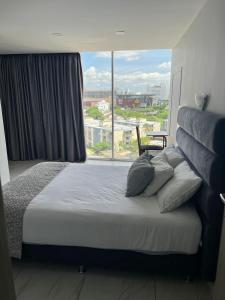 a bedroom with a bed with a large window at Hotel OR Suites in Barranquilla