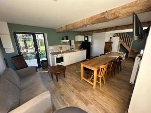 a kitchen and living room with a table and chairs at Gite de groupe confortable et lumineux - La ferme de Montigny in Neauphe-sur-Dives