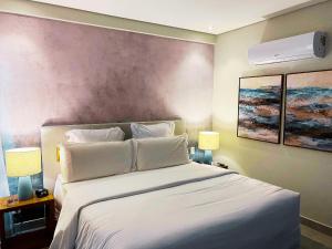 um quarto com uma grande cama branca com duas lâmpadas em Flat Île de Pipa Varanda - By Almare em Pipa mais 15 fotografias