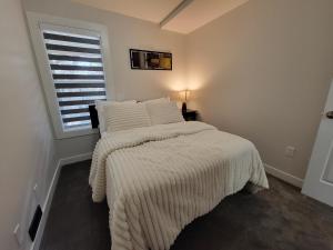 a bedroom with a bed with white blankets and a window at Walkout Basement Suite in Calgary