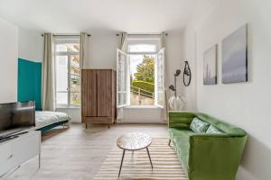 een woonkamer met een groene bank en een televisie bij Studio proche plage in Sainte-Adresse