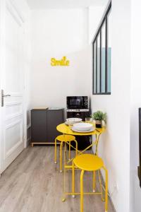 een keuken met gele stoelen, een tafel en een fornuis bij Studio proche plage in Sainte-Adresse