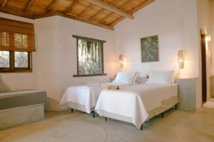 a bedroom with two beds with white sheets and a window at Ventos Morere Hotel & Beach Club in Ilha de Boipeba