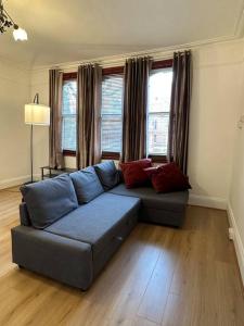 a living room with a blue couch and two windows at Flat espaçoso 3min do metro in London