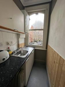 a small kitchen with a sink and a window at Flat espaçoso 3min do metro in London