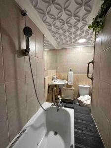 a bathroom with a tub and a sink and a toilet at Flat espaçoso 3min do metro in London