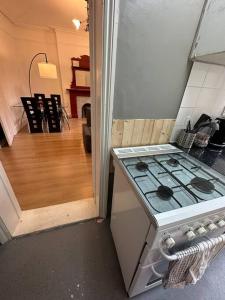a kitchen with a stove and a room with a floor at Flat espaçoso 3min do metro in London