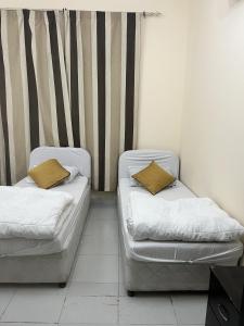 two beds sitting in a room with a wall at Short Term Tourist Place in Dubai