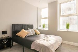 een bed in een slaapkamer met 2 ramen bij Stunning Central Apartment In Heart Of Brighton in Brighton & Hove