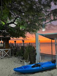 um caiaque azul sentado na praia ao pôr do sol em Solita beach bungalow - kite spot em Macau