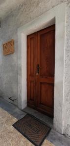 uma porta de madeira de um edifício com um tapete na frente em AL CASTANEDO em Domodossola