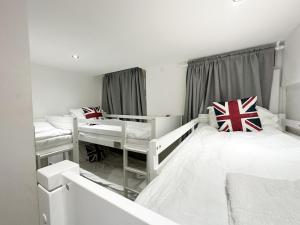 Cette chambre blanche dispose de deux lits et d'une fenêtre. dans l'établissement 205 Earls Court Rooms, à Londres